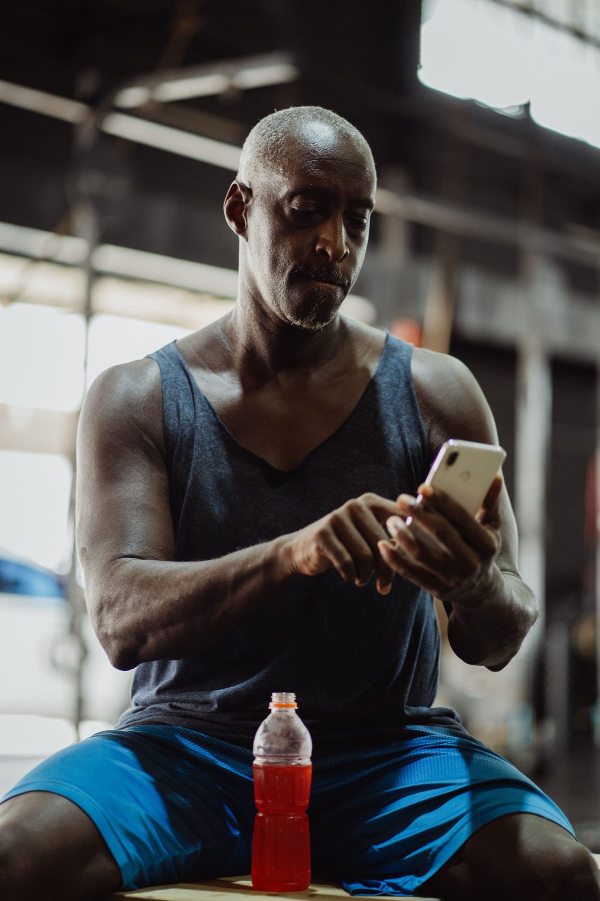 A player sitting in the gym, checking a phone between drills